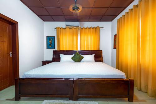 a bedroom with a large bed with orange curtains at Okumah Hotel in Kumasi