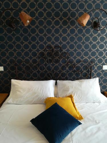 a bed with white pillows and a black wall at Le Régence in Arles