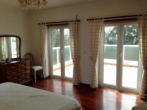 um quarto com portas e janelas com uma cama e pisos em madeira em Wavin' Trees Ericeira em Ericeira