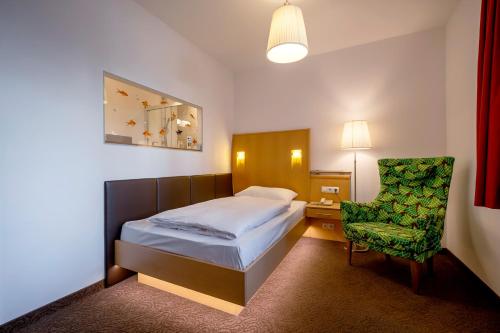 a hotel room with a bed and a chair at Strandhotel Alte Donau in Vienna