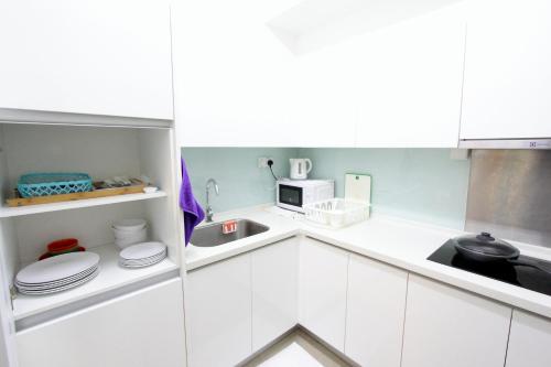 a white kitchen with a sink and a microwave at Afiniti Residensi Legoland Medini in Nusajaya