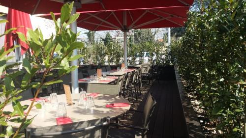 a row of tables and chairs with a red umbrella at Best Western Plus Hôtel & Spa de Chassieu in Chassieu