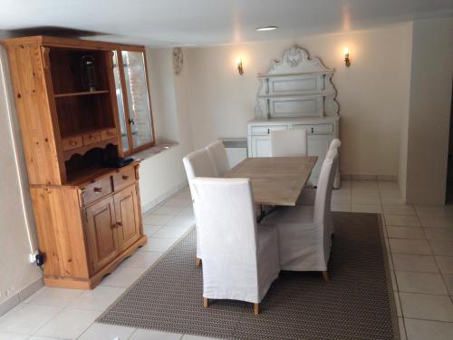 a dining room with a wooden table and white chairs at Eymet Townhouse in Eymet