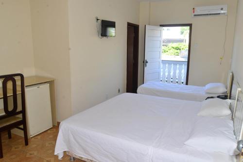 a bedroom with two beds and a chair and a window at HOTEL D' LUCCA in Ubá