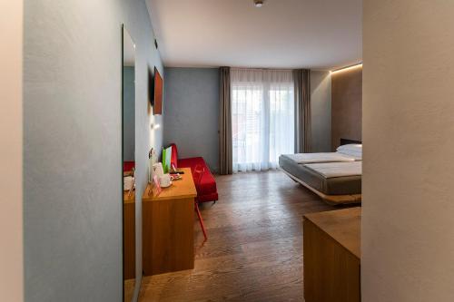 a room with a bedroom with a bed and a desk at Ambienthotel PrimaLuna 3S in Malcesine