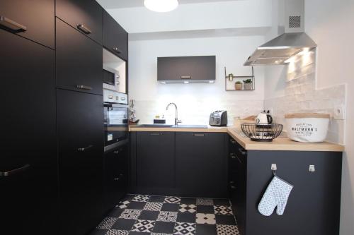 a kitchen with black cabinets and a tile floor at 3 Pièces à 50 mètres du bord de mer in Saint Malo