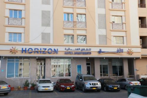 a hotel with cars parked in front of it at Horizon Hotel Apartments - الأفق للشقق الفندقية in Al Khawḑ