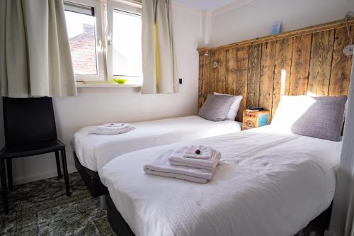 2 Betten in einem Zimmer mit Handtüchern darauf in der Unterkunft Pension de Wadvaarder in Midsland