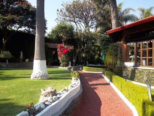 a garden with a palm tree and a brick walkway at Posada Los Alcatraces in Atlixco