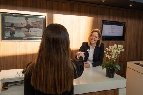 a woman is talking to a woman at a counter at Novotel Cardiff Centre in Cardiff