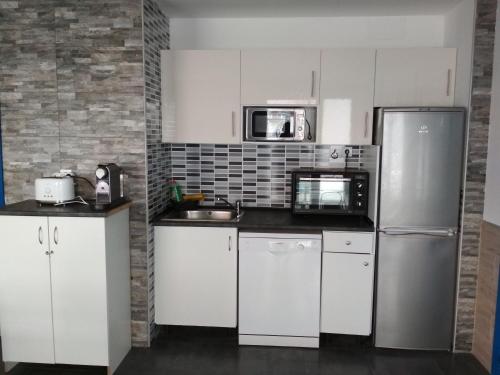 uma cozinha com armários brancos e um frigorífico de aço inoxidável em galerna aterpetxea em Zarautz