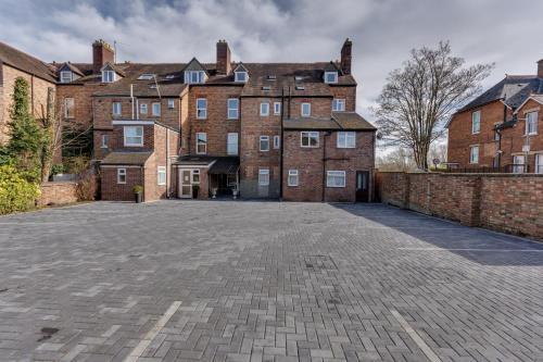 an empty parking lot in front of a large brick building at The Sportsview Guest House in Oxford