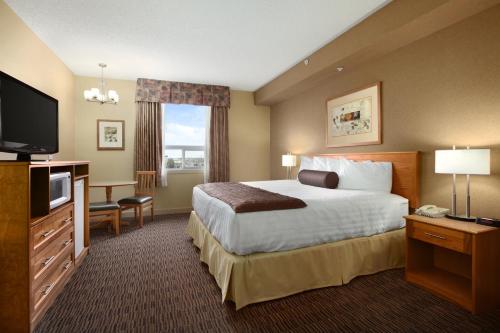 a hotel room with a bed and a flat screen tv at Days Inn & Suites by Wyndham West Edmonton in Edmonton