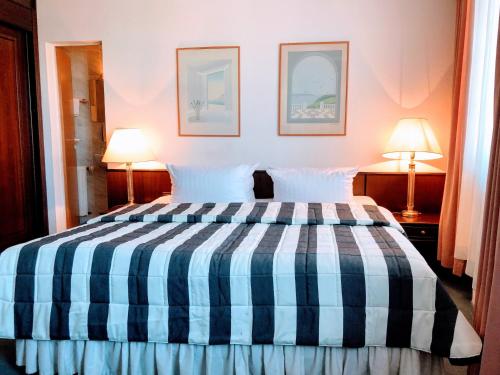 a bedroom with a blue and white bed with two lamps at Hotel Kölner Hof in Dormagen