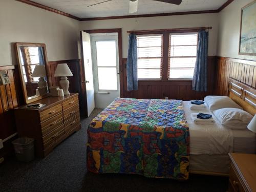 a bedroom with a bed and a dresser and a mirror at Cavalier by the Sea in Kill Devil Hills