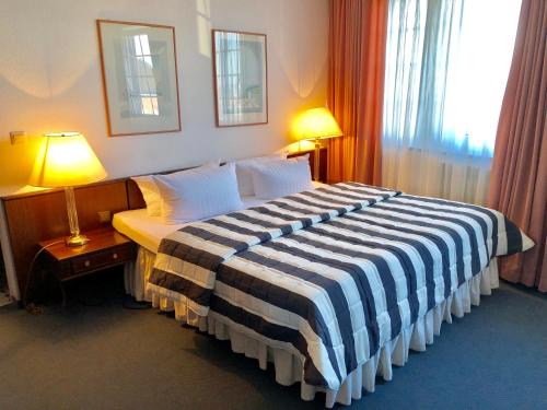 a hotel room with a bed with a striped blanket at Hotel Kölner Hof in Dormagen