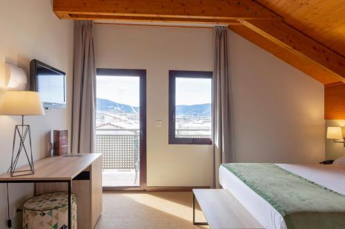 a bedroom with a bed and a desk and windows at Hotel & Spa Real Jaca in Jaca