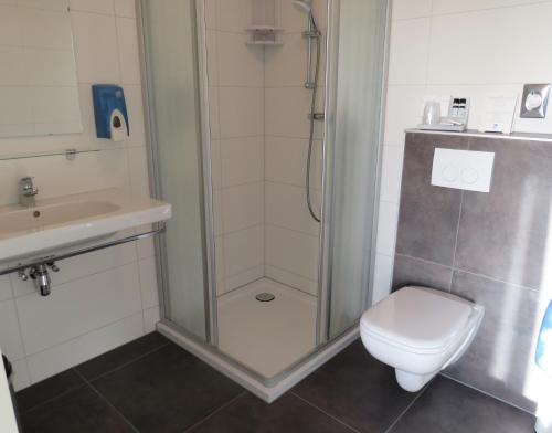 een badkamer met een douche, een toilet en een wastafel bij Seehotel Oostkapelle in Oostkapelle