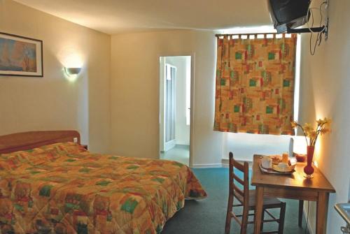 Habitación de hotel con cama, mesa y ventana en Hotel de Bordeaux, en Gramat