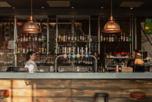 a bar with two women sitting at a counter at Novotel Cardiff Centre in Cardiff
