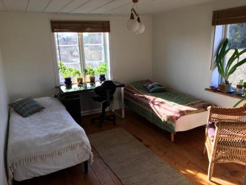 a bedroom with two beds and a desk and windows at Charming house on large property on Vato in Vätö