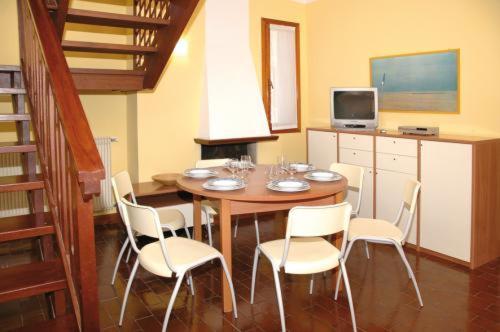 a dining room with a table and white chairs at Villa delle Terme in Lignano Sabbiadoro