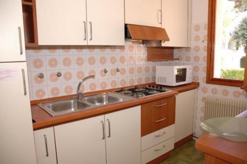 a kitchen with a sink and a microwave at Villa delle Terme in Lignano Sabbiadoro