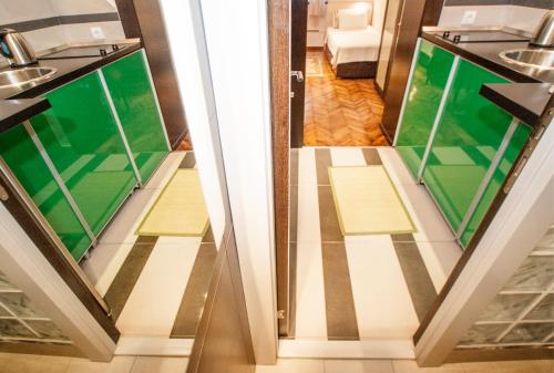 un bagno con pavimenti verdi e bianchi e uno specchio di Piano Cube a Belgrado