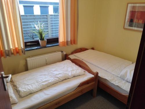 Duas camas num quarto com uma janela em Strandnahe Ferienwohnung Duhnen - Garten, Strandkorb, 4 Personen em Cuxhaven