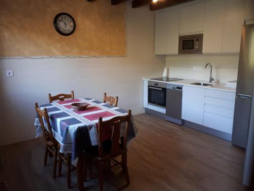 a kitchen with a table with chairs and a clock on the wall at APARTAMENTOS CAMINO SANTO TORIBIO in Mieses