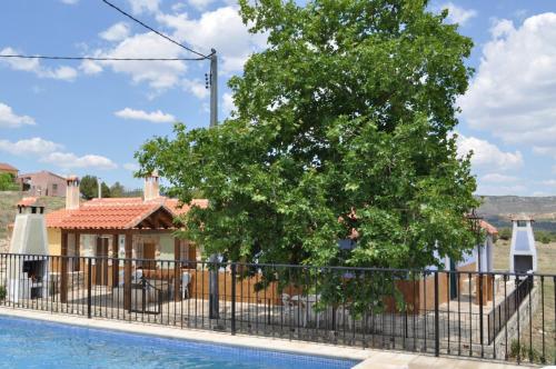 a tree next to a fence next to a pool at El Calar - Casas Rurales Luis in Moratalla