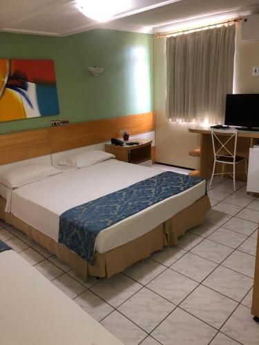 a bedroom with a bed and a desk and a computer at Raio de Sol Praia Hotel in Fortaleza