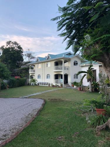 a large white house with a large yard at Flower Garden Self-Catering Apartments in Beau Vallon