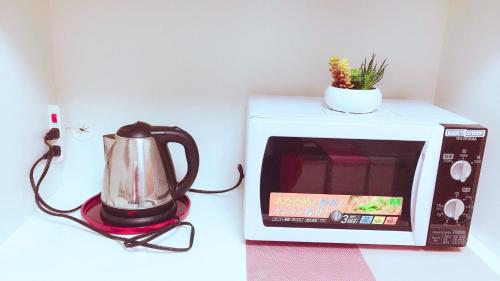 a microwave with a tea kettle on top of it at yikebukuro LuckyHouse 池袋一軒家 幸運の家 in Tokyo