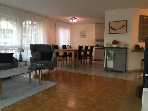 a living room with a table and chairs and a kitchen at Lake View Apartment in Faulensee