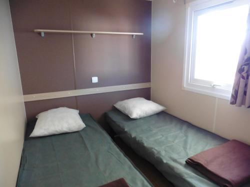 deux lits dans une petite pièce avec une fenêtre dans l'établissement Mobil Home Méditerranée avec terrasse, à Vic-la-Gardiole