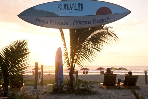 a sign on the beach with people sitting in chairs at Hotel Kundalini in Montañita