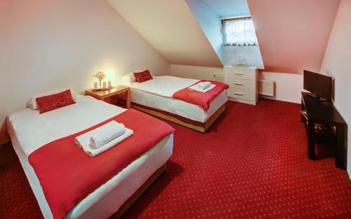 ジュコボにあるRestauracja Sidłoの赤いカーペットフロアのベッドルーム1室(ベッド2台付)