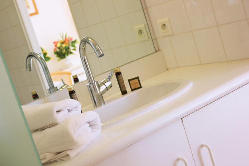 een witte badkamer met een wastafel en een spiegel bij Le Verdon in Gréoux-les-Bains