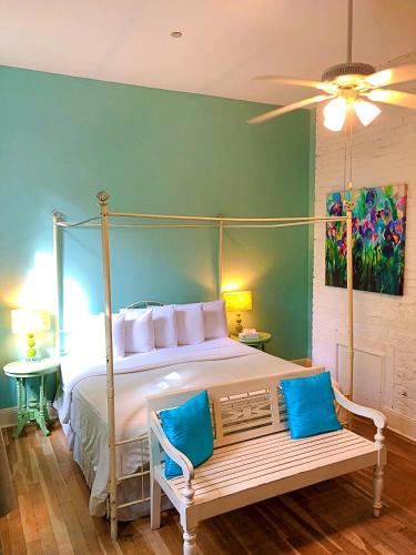 a bedroom with a canopy bed with blue pillows and a bench at Creole Gardens Guesthouse and Inn in New Orleans
