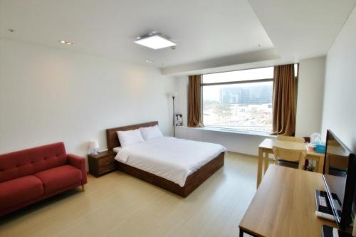a hotel room with a bed and a red couch at Incheon Airport Guesthouse in Incheon