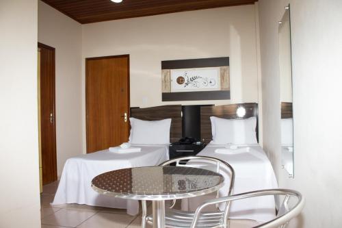 a room with two beds and a table and chairs at Gabvini Hotel in Lima Duarte