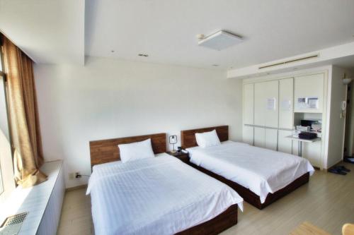 a bedroom with two beds with white sheets at Incheon Airport Guesthouse in Incheon