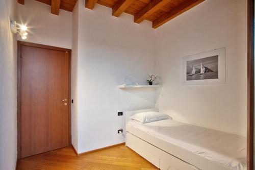 a white bedroom with a bed and a wooden door at COZY LAKE COMO APARTMENTS in Valmadrera