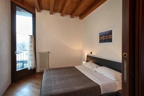 een slaapkamer met een bed en een groot raam bij COZY LAKE COMO APARTMENTS in Valmadrera