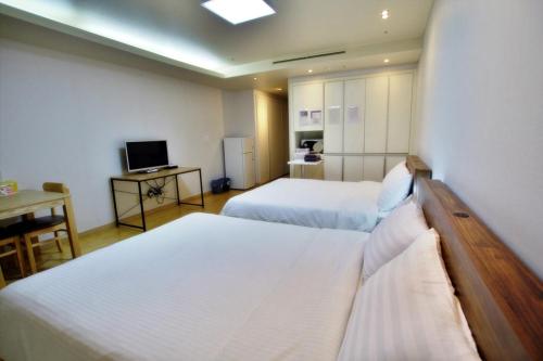 a hotel room with two beds and a television at Incheon Airport Guesthouse in Incheon