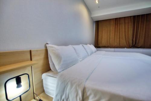 a bedroom with a white bed with a light on it at Incheon Airport Guesthouse in Incheon