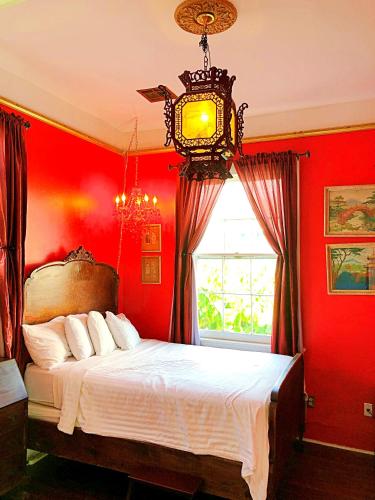 a bedroom with red walls and a bed with a clock at Creole Gardens Guesthouse and Inn in New Orleans