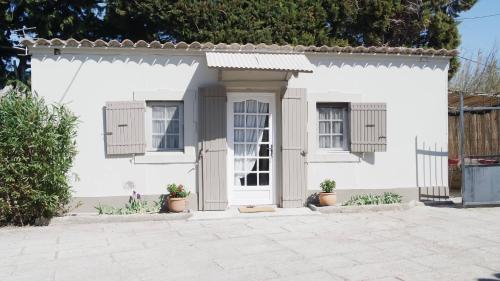 a white house with two windows and potted plants at Mas Grimaud - Gîte- Studio et chambres d'hôtes familiales in Eygalières