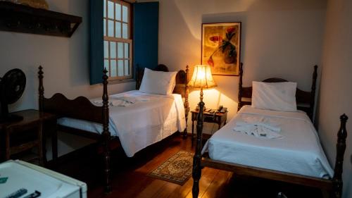 a bedroom with two beds and a lamp in it at Pousada Solar da Inconfidência - fácil acesso a Praça Tiradentes in Ouro Preto